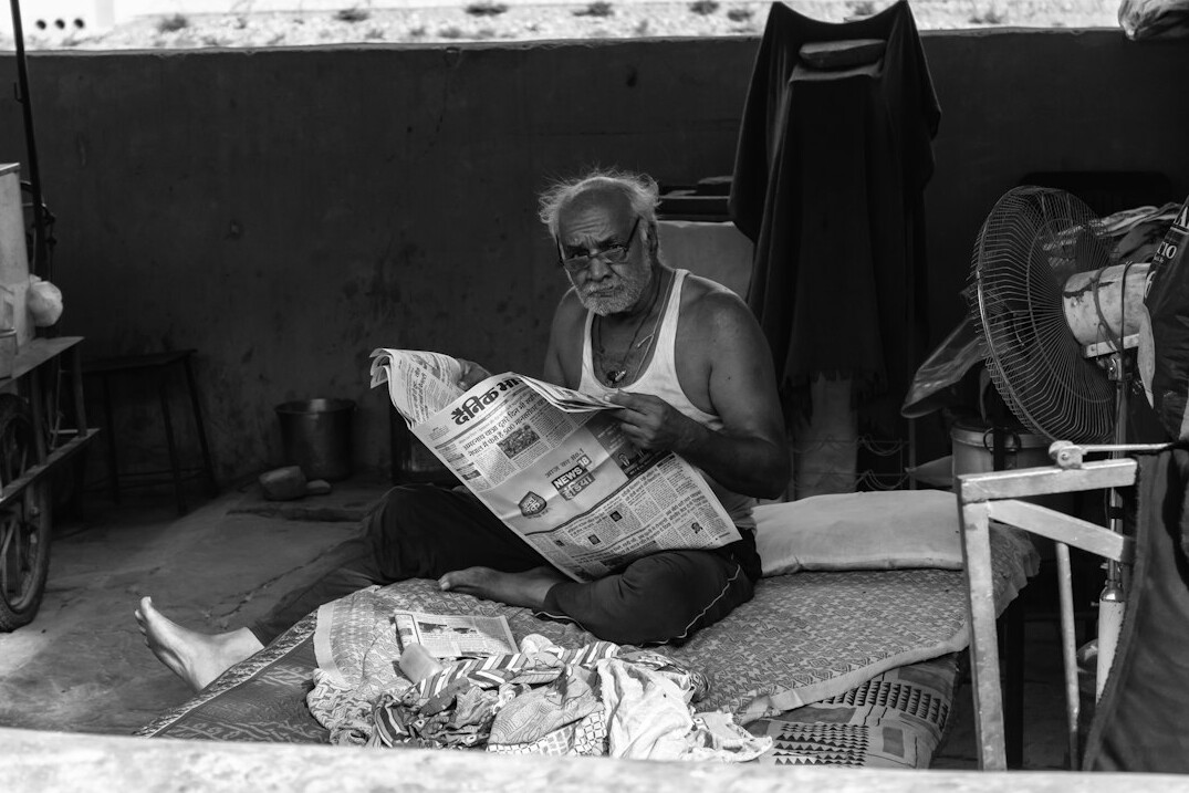 elderly man selling newspapers